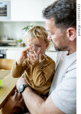 Young child and dad eating healthy snack during playful family moment. 139551413