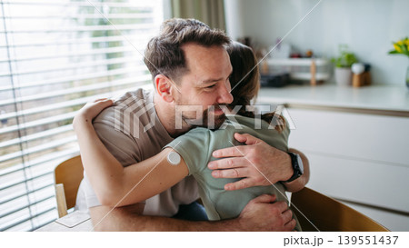 Dad hugging with daughter with diabetes in kitchen at home. Dad hugging with daughter with diabetes in kitchen at home. 139551437