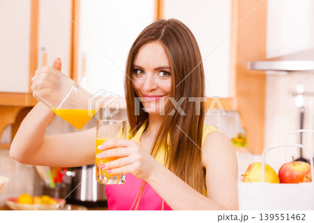 Woman make orange juice in juicer machine pouring drink in glass 139551462