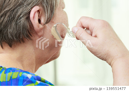 Closeup senior woman using hearing aid Closeup senior woman using hearing aid 139551477