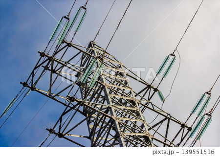 Robust high-voltage power lines and sturdy transmission tower extend skyward, showcasing vital electricity infrastructure with striking glass insulators against a shifting sky Robust high-voltage power lines and sturdy transmission tower extend skyward, showcasing vital electricity infrastructure with striking glass insulators against a shifting sky 139551516