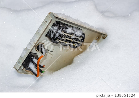 Roughly disassembled electrical enclosure, its guts exposed and buried in a pristine blanket of snow. Winter scene of forgotten electronic waste outdoors 139551524