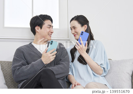 リビングでスマホを持って会話するカップル 139551670