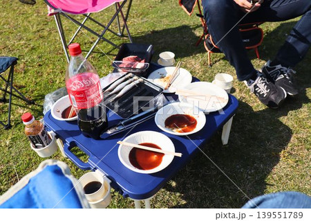 芝生の上に並ぶアウトドア食事セットとテーブルの風景 芝生の上に並ぶアウトドア食事セットとテーブルの風景 139551789