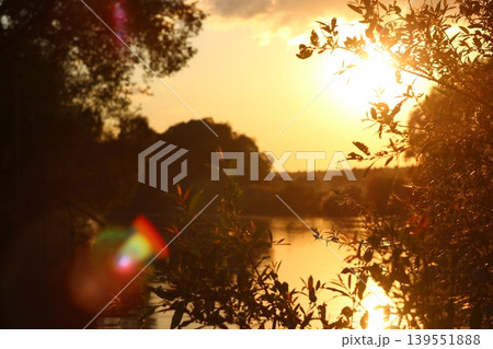Bright orange sunlight during sunset over the river, beautiful highlights Bright orange sunlight during sunset over the river, beautiful highlights 139551888