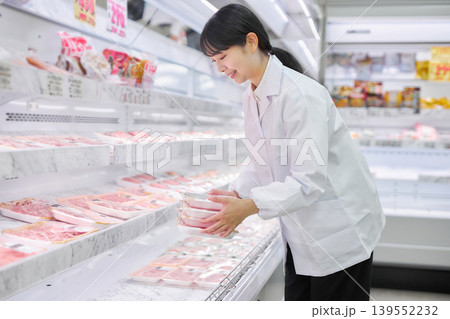 スーパーマーケットでお肉の品出しをする白衣の若い女性 スーパーマーケットでお肉の品出しをする白衣の若い女性 139552232