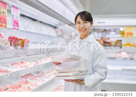 スーパーマーケットでお肉の品出しをする白衣の若い女性 スーパーマーケットでお肉の品出しをする白衣の若い女性 139552233
