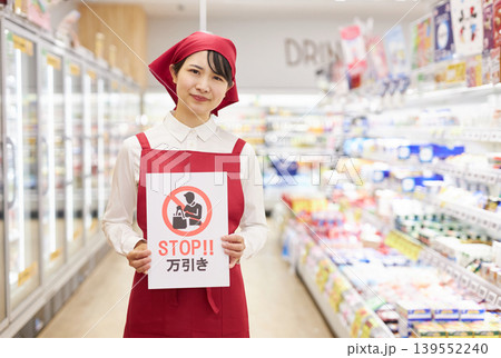 スーパーマーケットの商品の前で万引き防止のプラカードを持つ若い女性 139552240