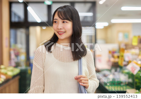 スーパーマーケットでスマホを見ながら買い物をする若い女性 139552413