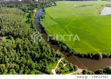 Scenic aerial view of a green landscape with a river separating the field and forest Scenic aerial view of a green landscape with a river separating the field and forest 139552502