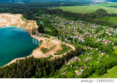 Aerial view of a settlement next to a lake formed on the site of a sand quarry, beautiful countryside landscape Aerial view of a settlement next to a lake formed on the site of a sand quarry, beautiful countryside landscape 139552551