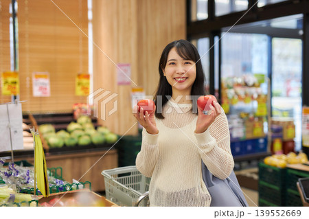 スーパーマーケットでスマホを見ながら買い物をする若い女性 スーパーマーケットでスマホを見ながら買い物をする若い女性 139552669
