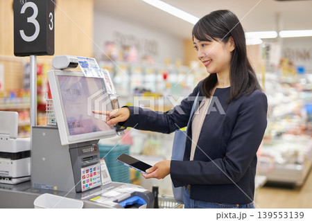 セルフレジでスマートフォン決済をする若い女性 セルフレジでスマートフォン決済をする若い女性 139553139