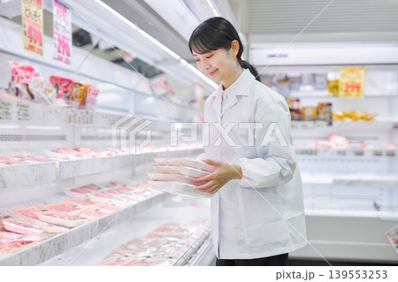 スーパーマーケットでお肉の品出しをする白衣の若い女性 スーパーマーケットでお肉の品出しをする白衣の若い女性 139553253
