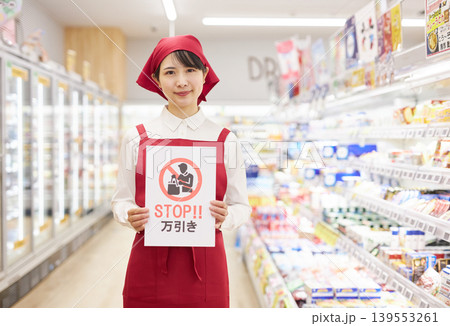 スーパーマーケットの商品の前で万引き防止のプラカードを持つ若い女性 スーパーマーケットの商品の前で万引き防止のプラカードを持つ若い女性 139553261