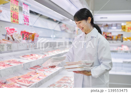 スーパーマーケットでお肉の品出しをする白衣の若い女性 139553475
