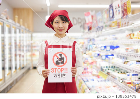 スーパーマーケットの商品の前で万引き防止のプラカードを持つ若い女性 スーパーマーケットの商品の前で万引き防止のプラカードを持つ若い女性 139553479
