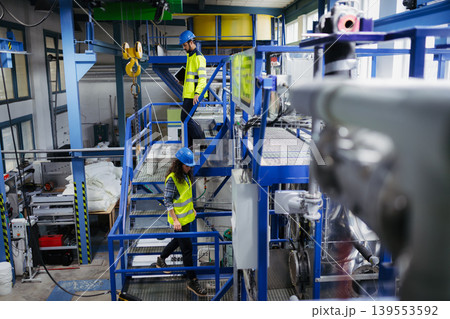 Industrial workers supervising automated manufacturing systems. 139553592