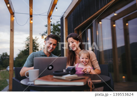 Modern family spending time together on patio, father using laptop. 139553624