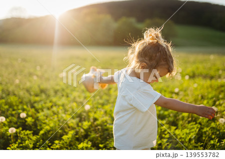 Cute girl playing on meadow, in spring nature. 139553782
