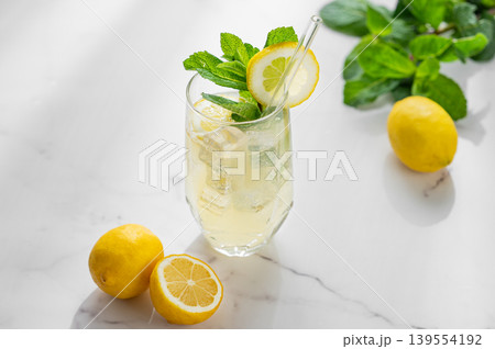 Refreshing lemon mint drink with ice in glass, homemade summer lemonade on marble background Refreshing lemon mint drink with ice in glass, homemade summer lemonade on marble background 139554192