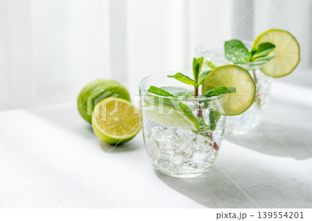 A fresh mojito with lime, mint and ice in glasses. Citrus lemonade or cocktail on a concrete table 139554201