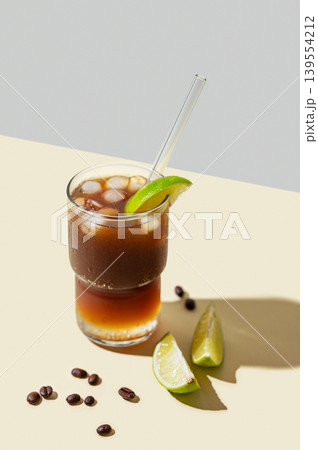 Cold Coffee Tonic Drink With Lime and Ice on light background with shadows Cold Coffee Tonic Drink With Lime and Ice on light background with shadows 139554212