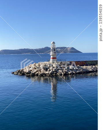 Lighthouse on rocky coastline with blue sea and clear sky, suitable as background image Lighthouse on rocky coastline with blue sea and clear sky, suitable as background image 139554859