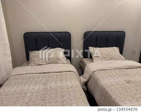 Twin beds with gray bedding in a simple bedroom interior background Twin beds with gray bedding in a simple bedroom interior background 139554870
