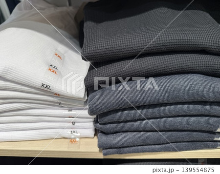 Folded clothes in assorted sizes on shelf display, showcasing retail organization background 139554875