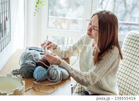 Woman knitting wool yarn at home for hobby Woman knitting wool yarn at home for hobby 139555419
