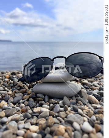 sunglasses with black round lenses lie on a smooth surface on the seashore 139555631