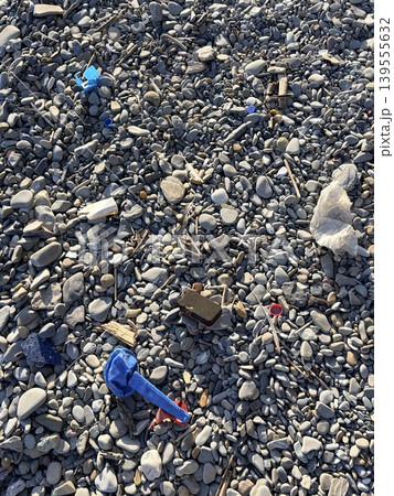 The pebble beach is strewn with plastic waste washed ashore by the sea. concept of environmental protection 139555632