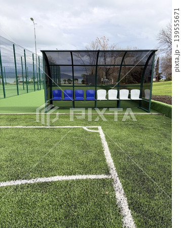 a soccer dugout situated on the sidelines of a sports field a soccer dugout situated on the sidelines of a sports field 139555671