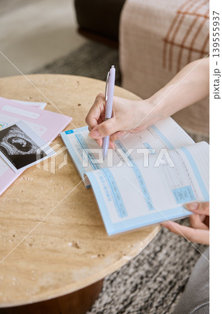 母子手帳に記入する妊婦の手元とエコー写真 139555937