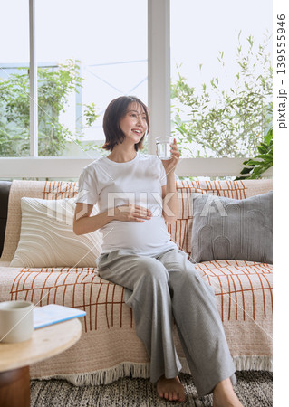 リビングのソファでグラスを持ちくつろぐ笑顔の女性 リビングのソファでグラスを持ちくつろぐ笑顔の女性 139555946