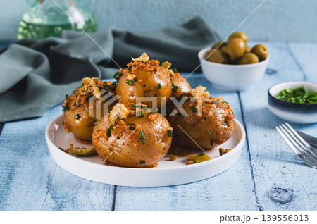 Baked new potatoes with herbs and olives on a plate on the table Baked new potatoes with herbs and olives on a plate on the table 139556013