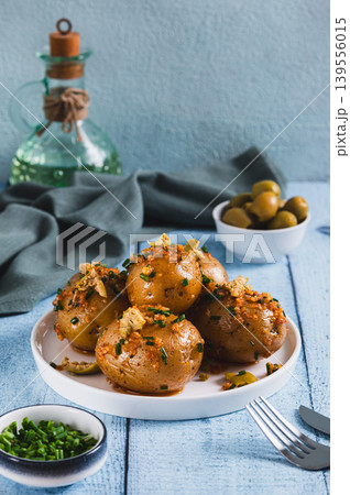 Baked new potatoes with herbs and olives on a plate on the table vertical view Baked new potatoes with herbs and olives on a plate on the table vertical view 139556015