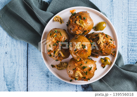 Close up of baked new potatoes with herbs and olives on a plate on the table top view Close up of baked new potatoes with herbs and olives on a plate on the table top view 139556018