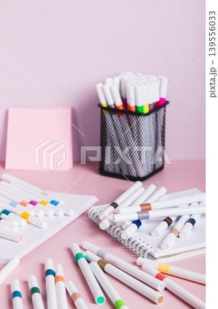 Colored acrylic markers for creativity and notebooks on the table vertical view Colored acrylic markers for creativity and notebooks on the table vertical view 139556033