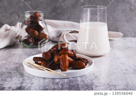 Sweet dates on a plate and a glass of milk on the table 139556040