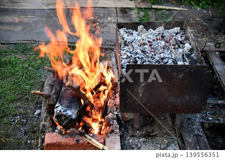 in a summer evening, two men in their forties prepares a barbecue for friends gathered around a table in a summer evening, two men in their forties prepares a barbecue for friends gathered around a table 139556351