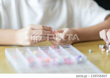 The bead activity supports careful finger movement, tactile practice, and cooperative learning while children create handmade jewelry from divided compartments. 139556807