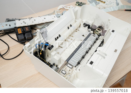 Disassembled printer interior with removed ink cartridges, exposed gears and electronics, illustrating maintenance, repair and technical troubleshooting of office printing equipment in close-up. 139557018
