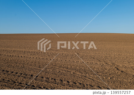 Wide view of agricultural field with tilled soil ready for planting crops under clear sky during daytime Wide view of agricultural field with tilled soil ready for planting crops under clear sky during daytime 139557257