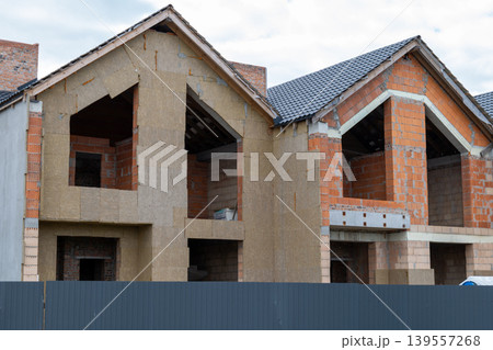 Construction work is ongoing on houses as builders use bricks and insulation materials in a developed housing project Construction work is ongoing on houses as builders use bricks and insulation materials in a developed housing project 139557268