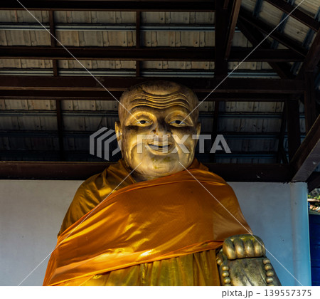 Quiet pavilion with large seated monk figure creates reflective stop for visitors exploring historic countryside landmarks, spiritual heritage sites, tropical cultural travel experiences. Quiet pavilion with large seated monk figure creates reflective stop for visitors exploring historic countryside landmarks, spiritual heritage sites, tropical cultural travel experiences. 139557375