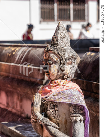 Weathered female guardian figure stands within a sacred temple site surrounded by historic stone structures and cultural heritage architecture. 139557379