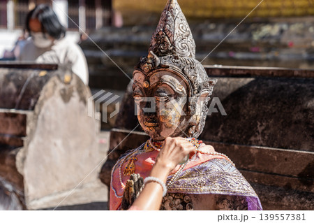 Weathered female guardian figure stands within a sacred temple site surrounded by historic stone structures and cultural heritage architecture. 139557381