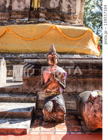 Weathered female guardian figure stands within a sacred temple site surrounded by historic stone structures and cultural heritage architecture. 139557384